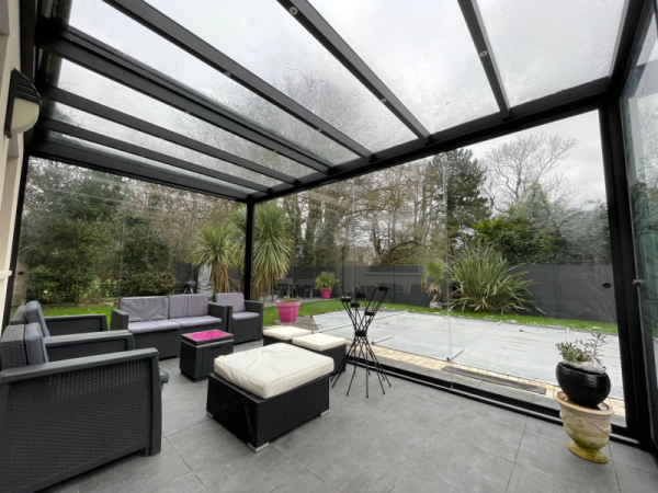 Véranda alu noir toit vitré incliné, parois coulissantes, terrasse dalles, piscine