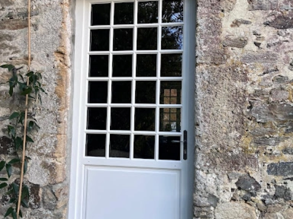 Porte d'entrée blanche petits bois 4x6 dans mur pierres naturelles multicolores