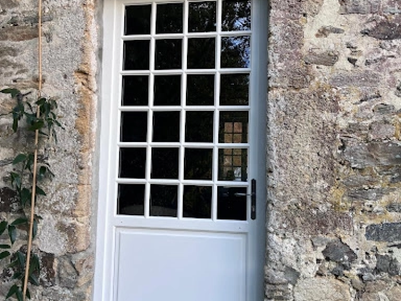 Porte d'entrée blanche petits bois 4x6 dans mur pierres naturelles multicolores