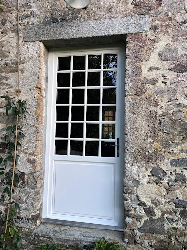 Porte d'entrée blanche petits bois 4x6 dans mur pierres naturelles multicolores