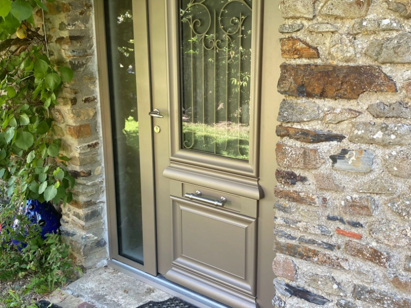 Porte d'entrée taupe, vitrage grille fer forgé, tierce vitrée et mur pierres