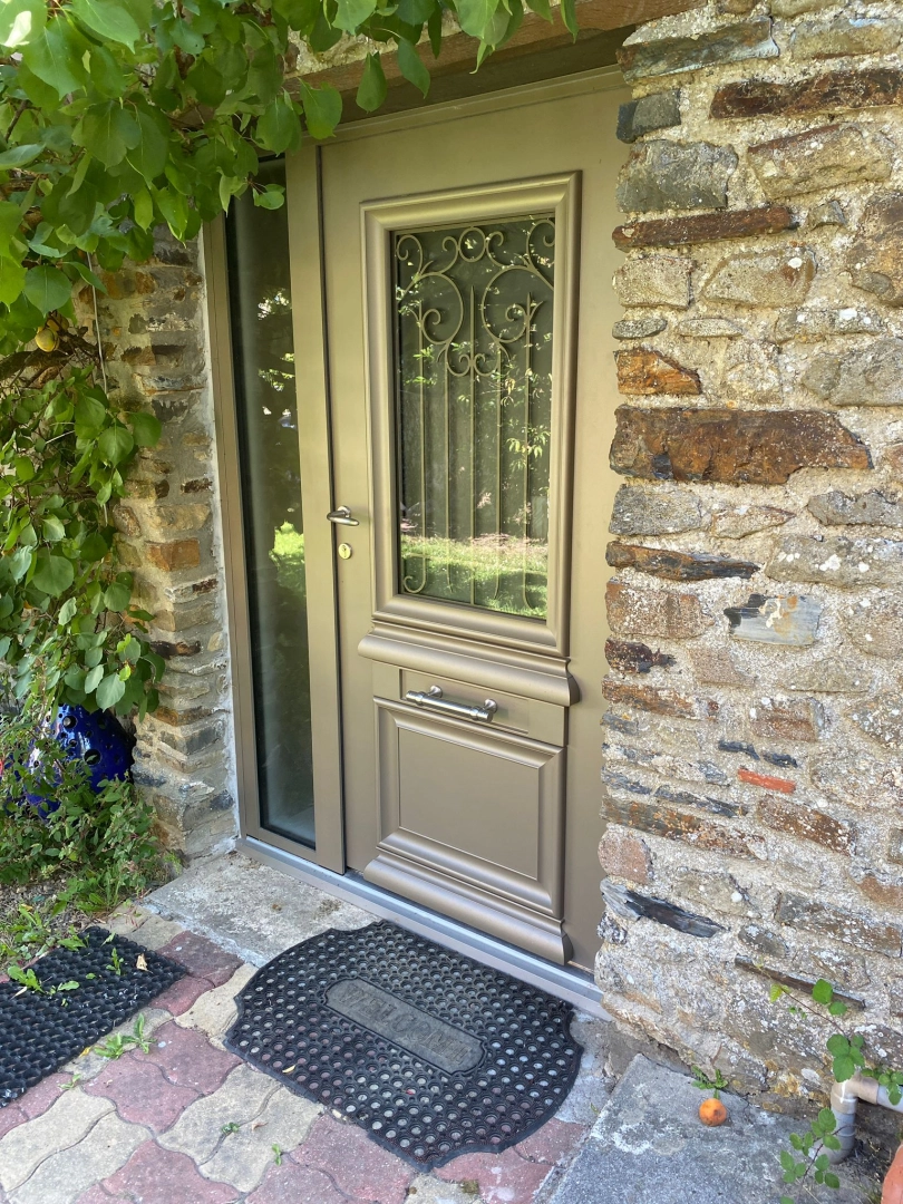Porte d'entrée taupe, vitrage grille fer forgé, tierce vitrée et mur pierres