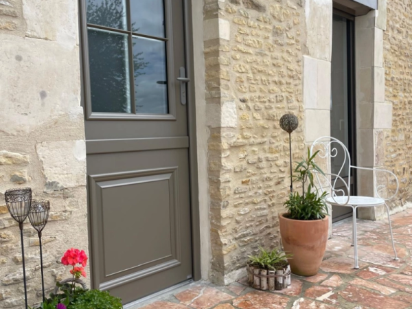 Porte d'entrée taupe semi-vitrée quatre carreaux dans mur en pierres apparentes beige