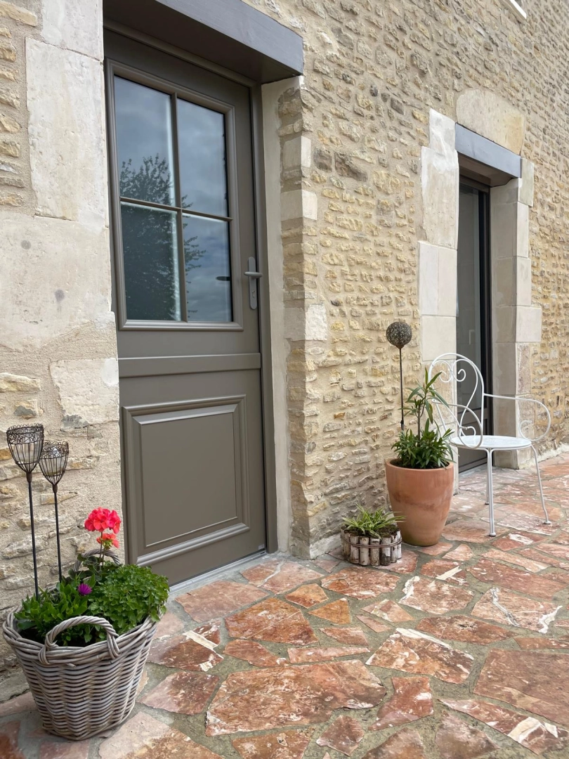 Porte d'entrée taupe semi-vitrée quatre carreaux dans mur en pierres apparentes beige