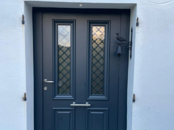 Porte d'entrée gris anthracite, vitrages givrés à grilles décoratives, cloche fer sur mur blanc