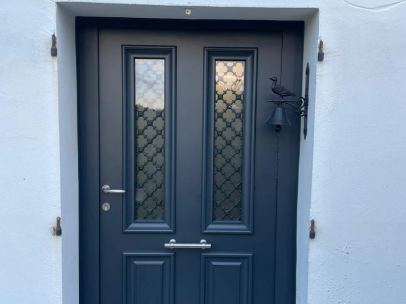 Porte d'entrée gris anthracite, vitrages givrés à grilles décoratives, cloche fer sur mur blanc
