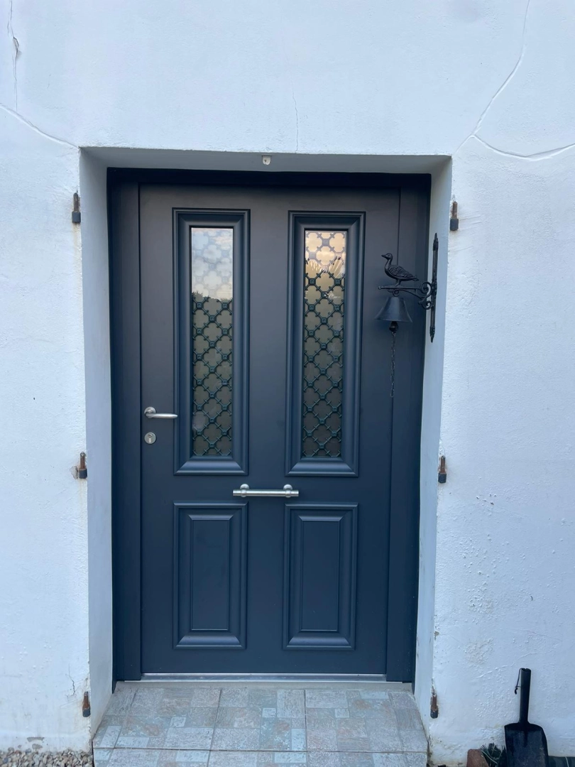 Porte d'entrée gris anthracite, vitrages givrés à grilles décoratives, cloche fer sur mur blanc