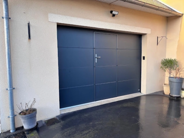 Porte sectionnelle garage anthracite avec portillon central intégré, façade crépi