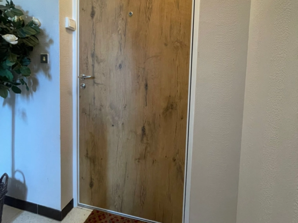 Porte palière intérieure effet bois clair, poignée chromée et judas sur carrelage