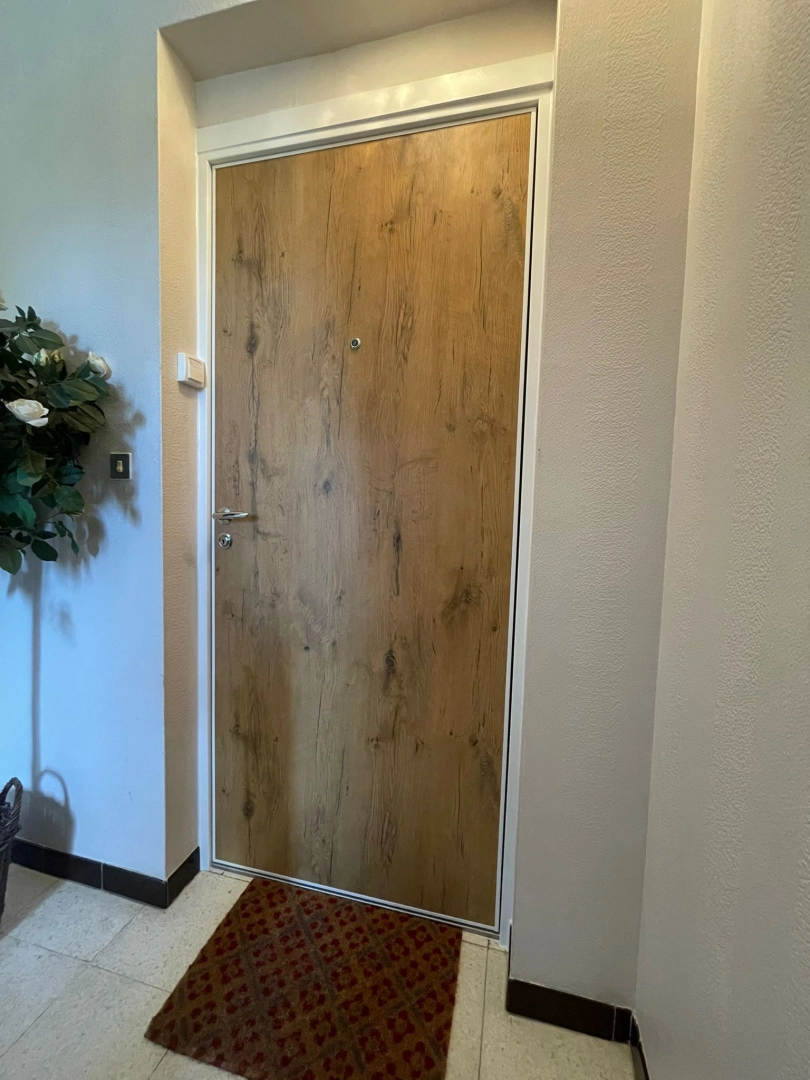 Porte palière intérieure effet bois clair, poignée chromée et judas sur carrelage