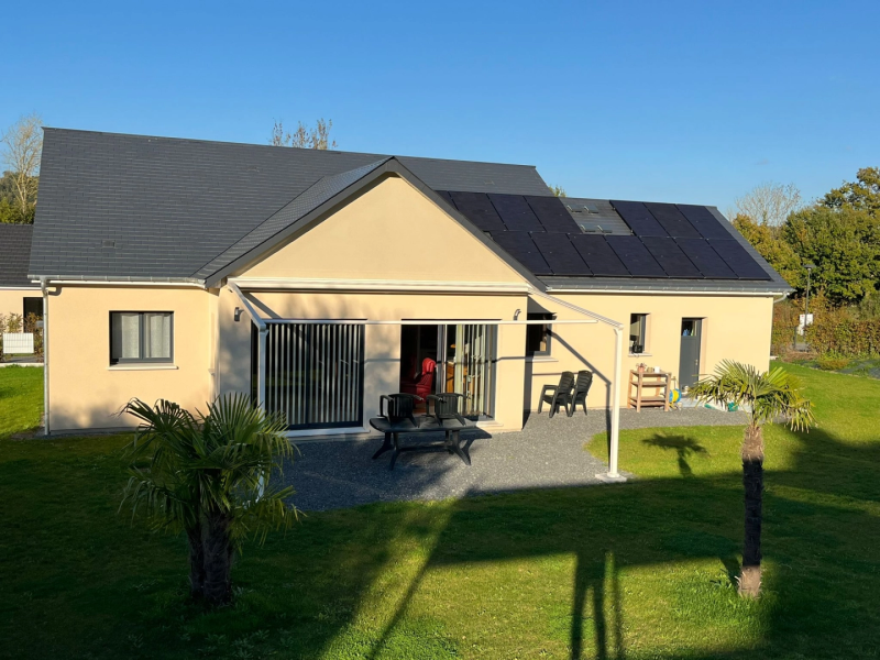 Storgola blanche, store vertical gris, terrasse gravier et panneaux solaires sur toiture ardoise