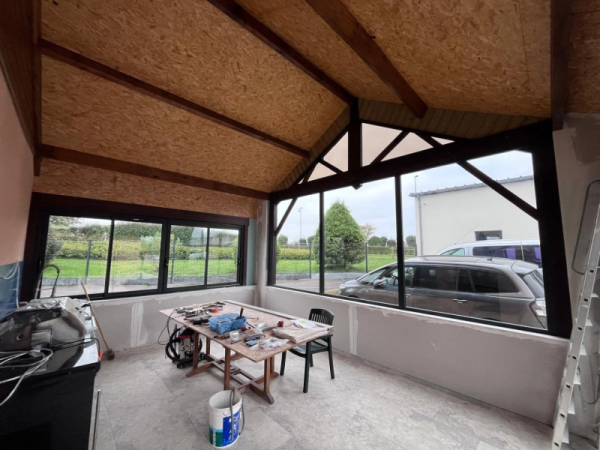 Extension en cours : grandes menuiseries alu noires, plafond OSB et murs placo non finis