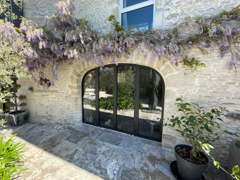 Baie coulissante trois vantaux alu noir cintrée, glycine violette sur pierre