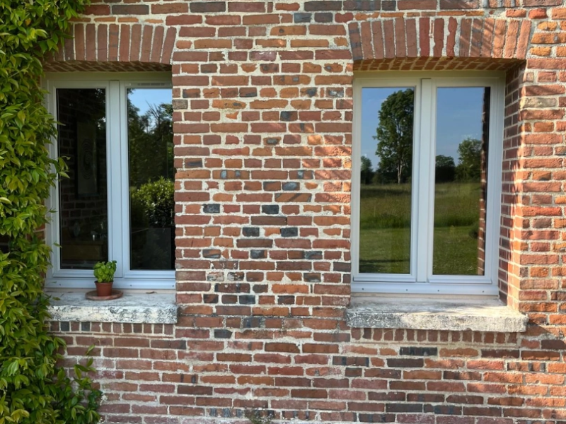 Deux fenêtres blanches posées dans mur briques rouges avec linteaux en arc