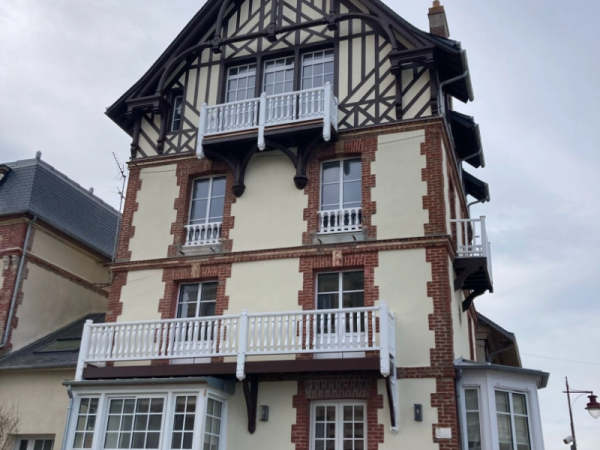 Maison briques et colombages : fenêtres blanches, garde-corps blancs et balcons
