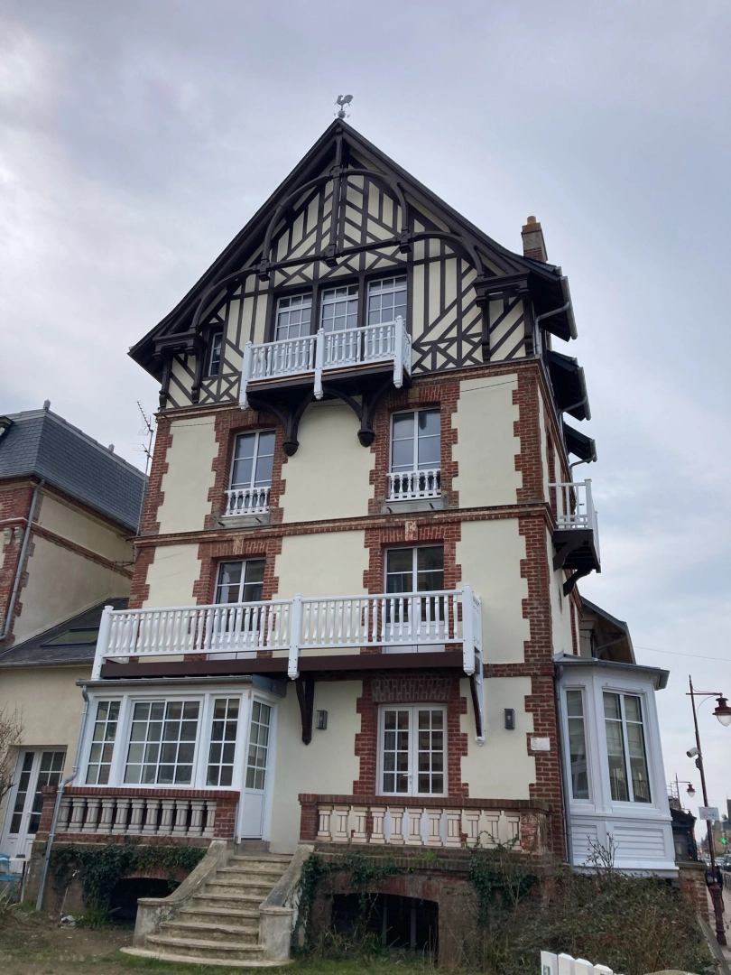Maison briques et colombages : fenêtres blanches, garde-corps blancs et balcons