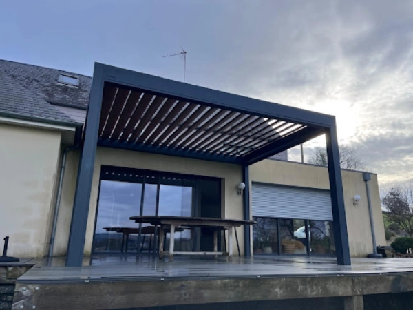 Pergola bioclimatique anthracite, lames ton bois, terrasse bois et table rustique