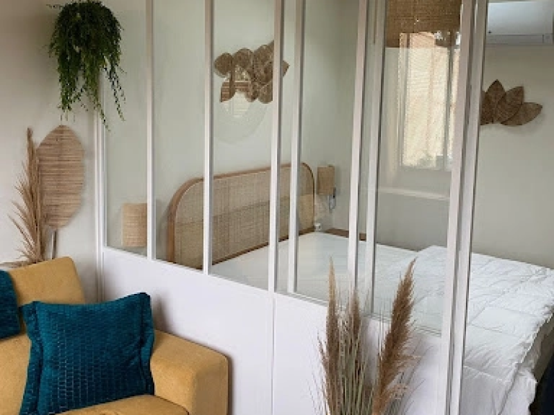Verrière intérieure blanche vitrée séparant coin nuit et salon jaune, décor bohème