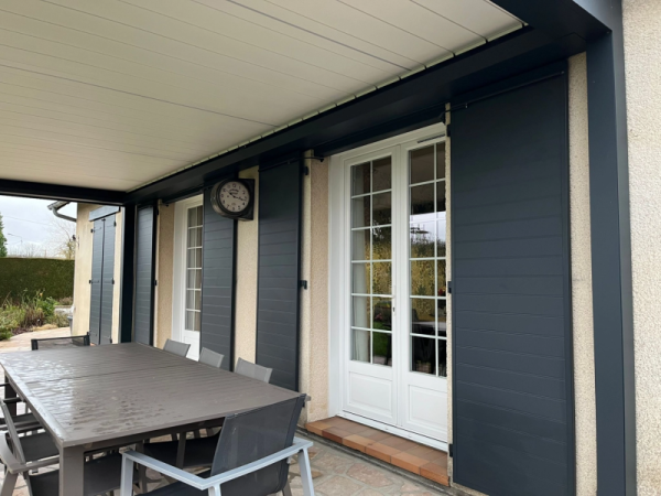 Pergola bioclimatique anthracite, lames blanches, stores coulissants et table pierre