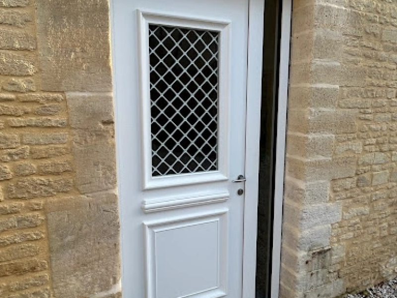 Porte d'entrée blanche grille losanges dans mur pierre beige traditionnel