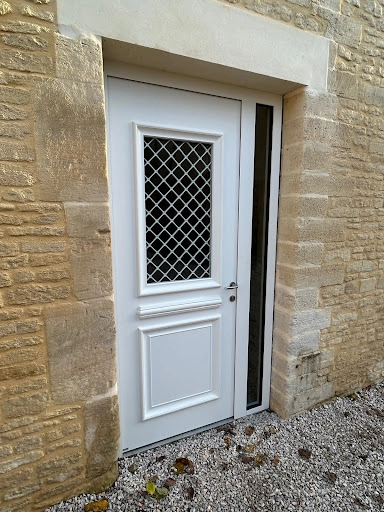 Porte d'entrée blanche grille losanges dans mur pierre beige traditionnel