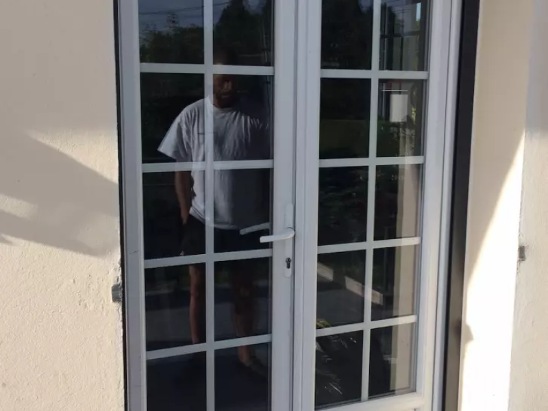 Porte-fenêtre blanche deux vantaux à petits bois, encadrement enduit beige clair