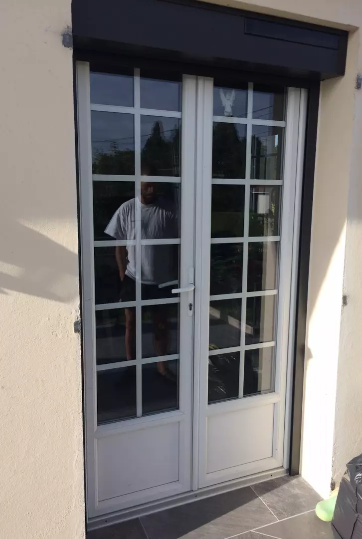 Porte-fenêtre blanche deux vantaux à petits bois, encadrement enduit beige clair