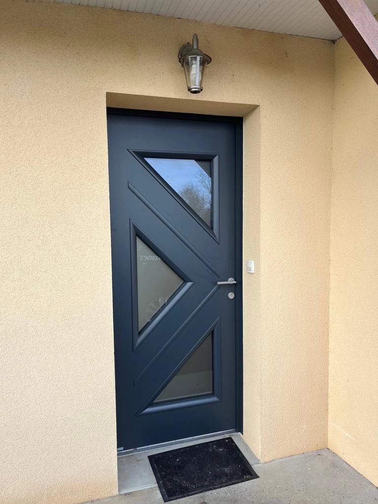 Porte d'entrée anthracite, trois vitrages triangulaires dépolis, enduit beige