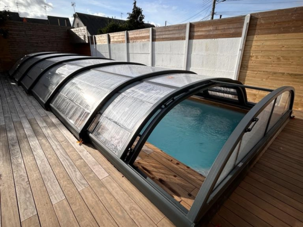 Abri piscine télescopique bas anthracite, partiellement ouvert, terrasse bois