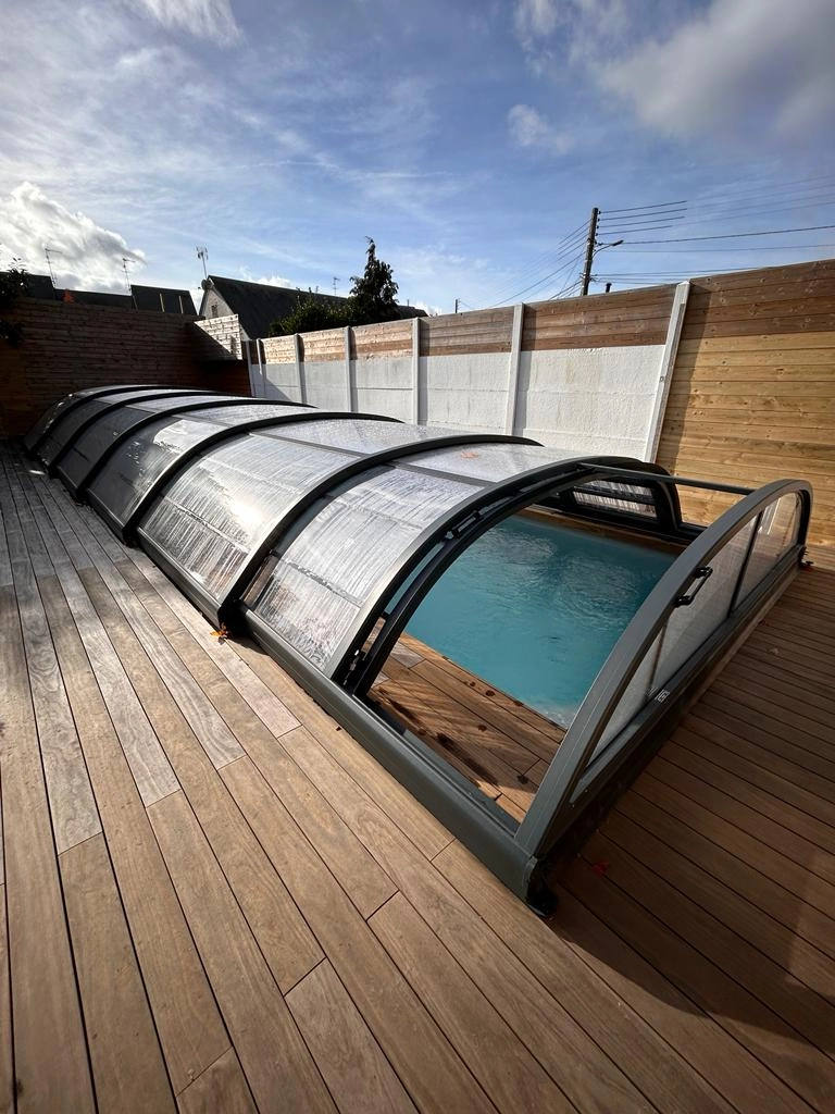 Abri piscine télescopique bas anthracite, partiellement ouvert, terrasse bois