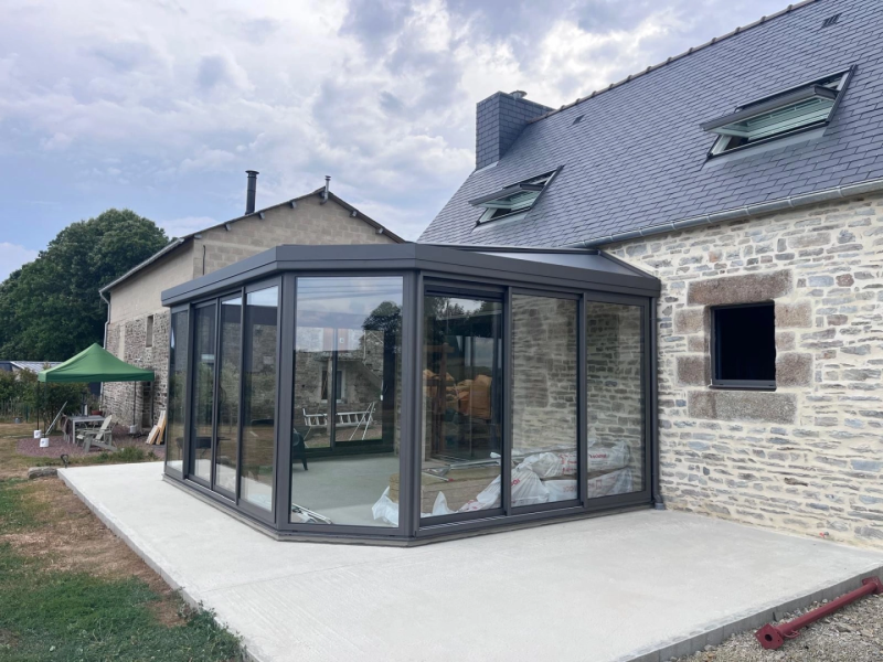 Véranda anthracite double toit sur dalle béton neuve, sacs isolant visibles