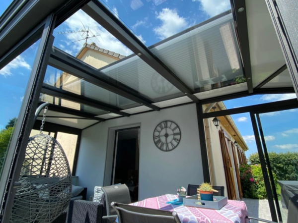 Véranda anthracite toit verre, stores roulants intégrés, salon et horloge murale