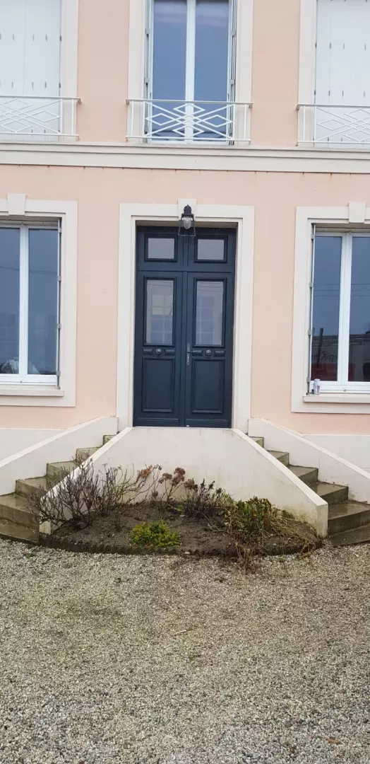 Porte d'entrée double bleu foncé vitrée, fenêtres blanches, façade saumon et marches béton