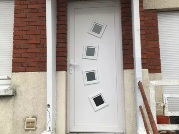 Porte d'entrée PVC blanche à quatre hublots carrés, façade briques rouges et enduit beige
