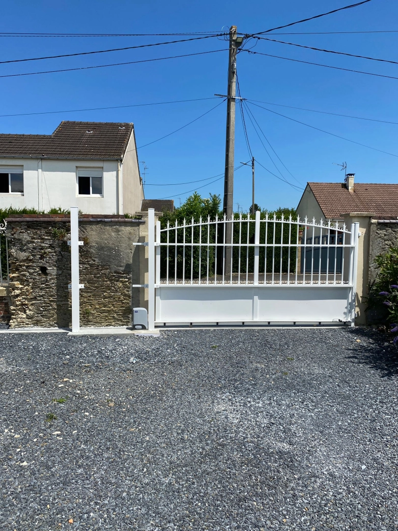 Portail coulissant blanc chapeau de gendarme, barreaudage et motorisation, murets en pierre