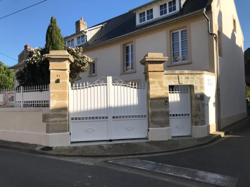Portail blanc festonné et portillon, piliers pierre, clôture barreaudée, maison crème