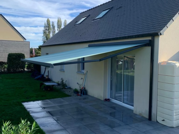 Store banne vert menthe, armature anthracite, terrasse carrelée, toiture ardoise