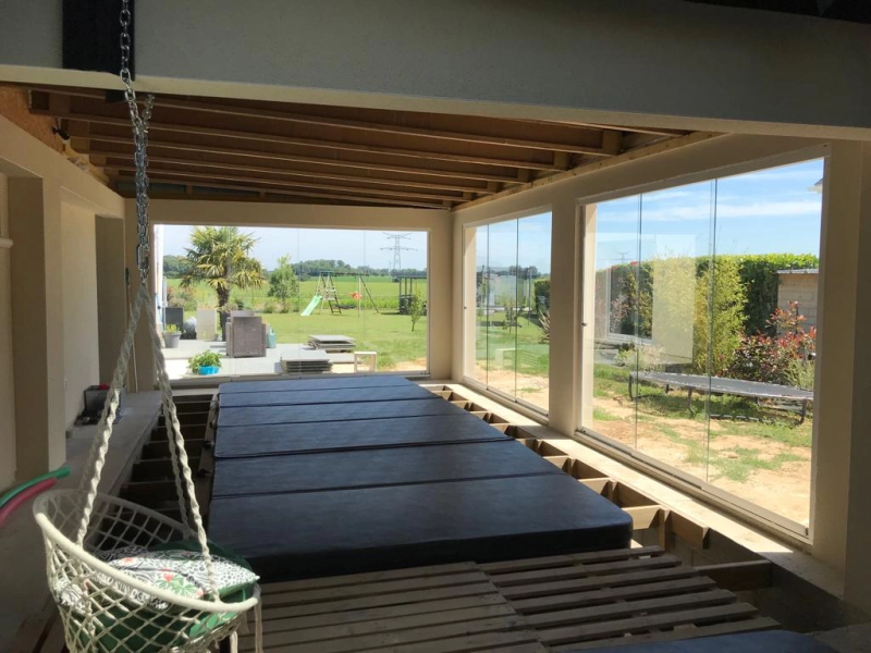 Paroi vitrée coulissante autour d'un spa encastré, plafond poutres bois, vue jardin