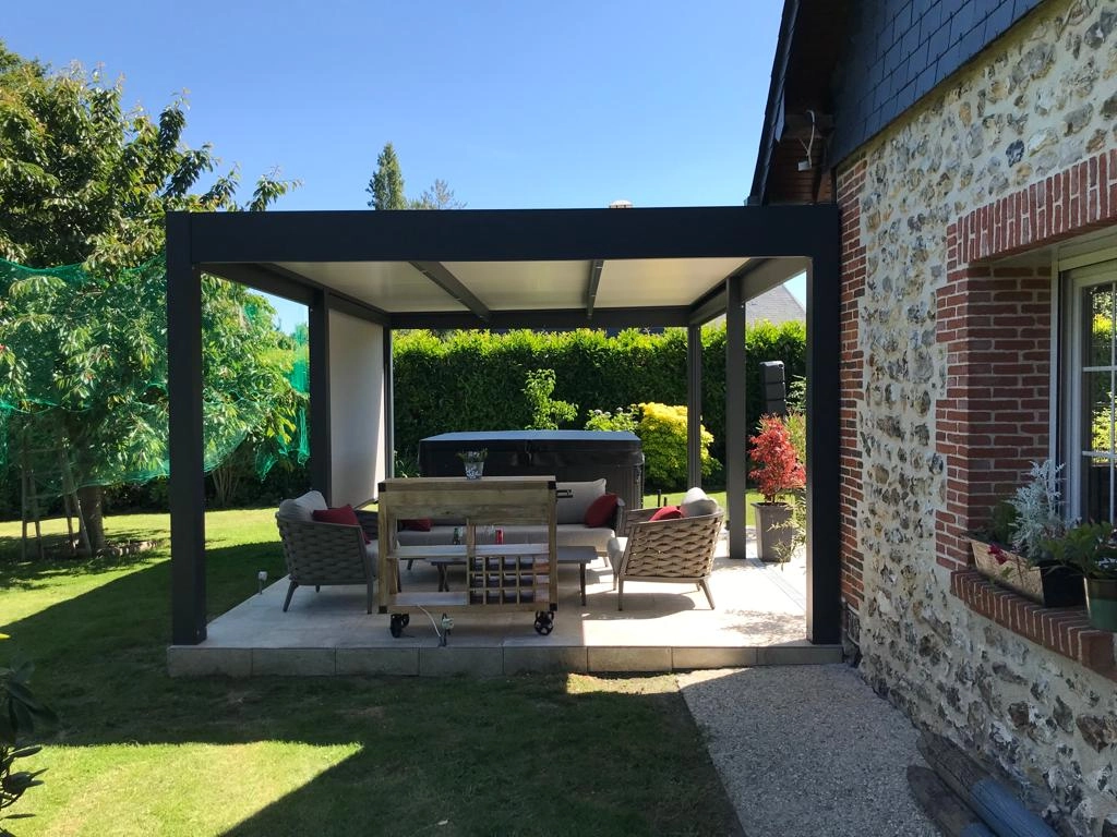 Pergola alu noir adossée à maison pierre, terrasse carrelée, spa et salon extérieur