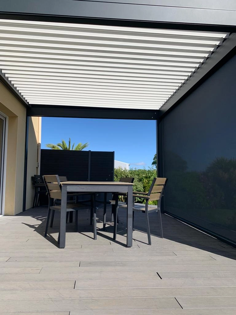 Pergola bioclimatique anthracite, lames blanches, screen latéral gris, table jardin