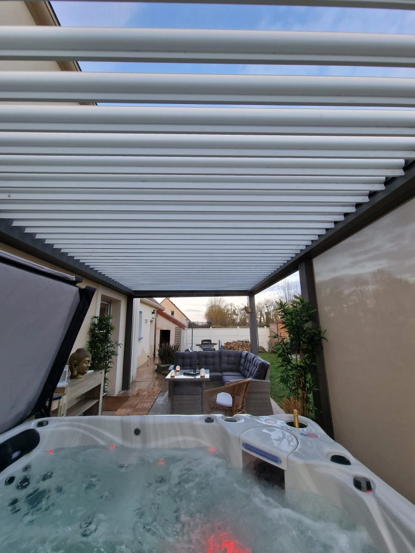 Pergola bioclimatique anthracite, lames blanches, salon et spa sous structure