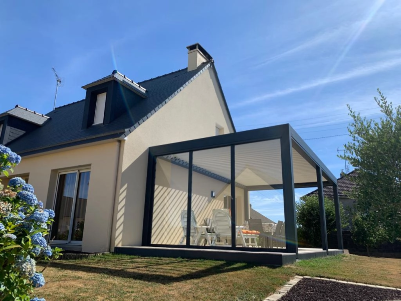 Pergola bioclimatique anthracite, baies vitrées, lames blanches, maison enduit beige