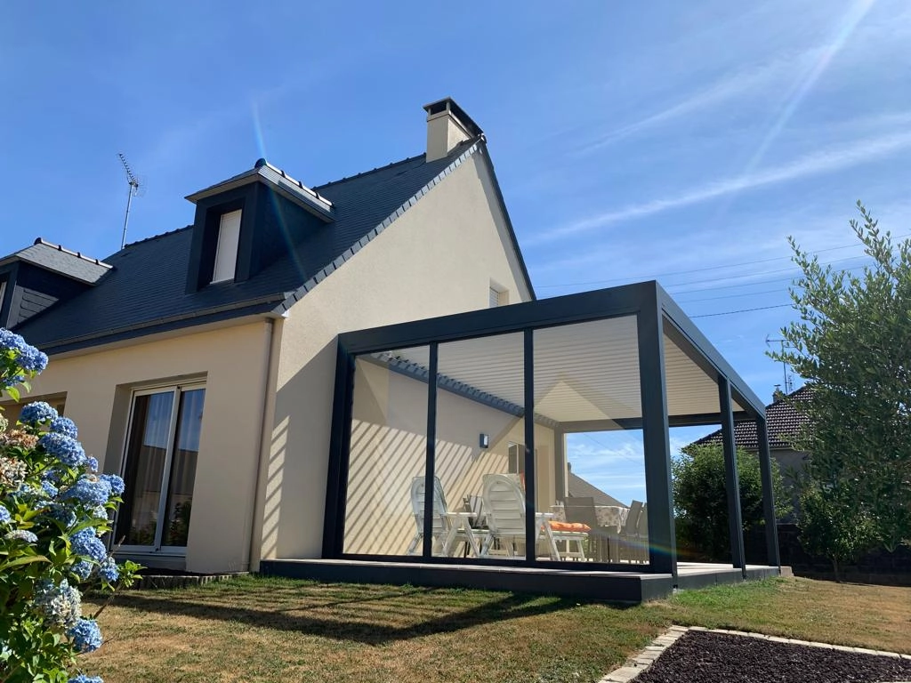 Pergola bioclimatique anthracite, baies vitrées, lames blanches, maison enduit beige