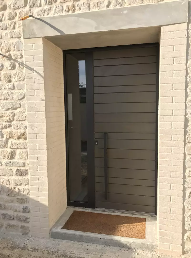 Porte d'entrée gris anthracite lames horizontales, imposte vitrée, encadrement briques claires