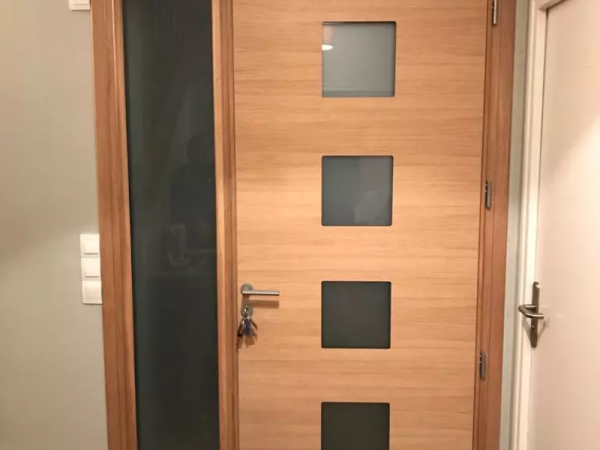 Porte d'entrée bois clair, imposte et quatre carreaux dépolis, poignée inox, vue intérieure