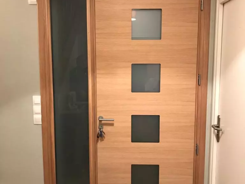 Porte d'entrée bois clair, imposte et quatre carreaux dépolis, poignée inox, vue intérieure