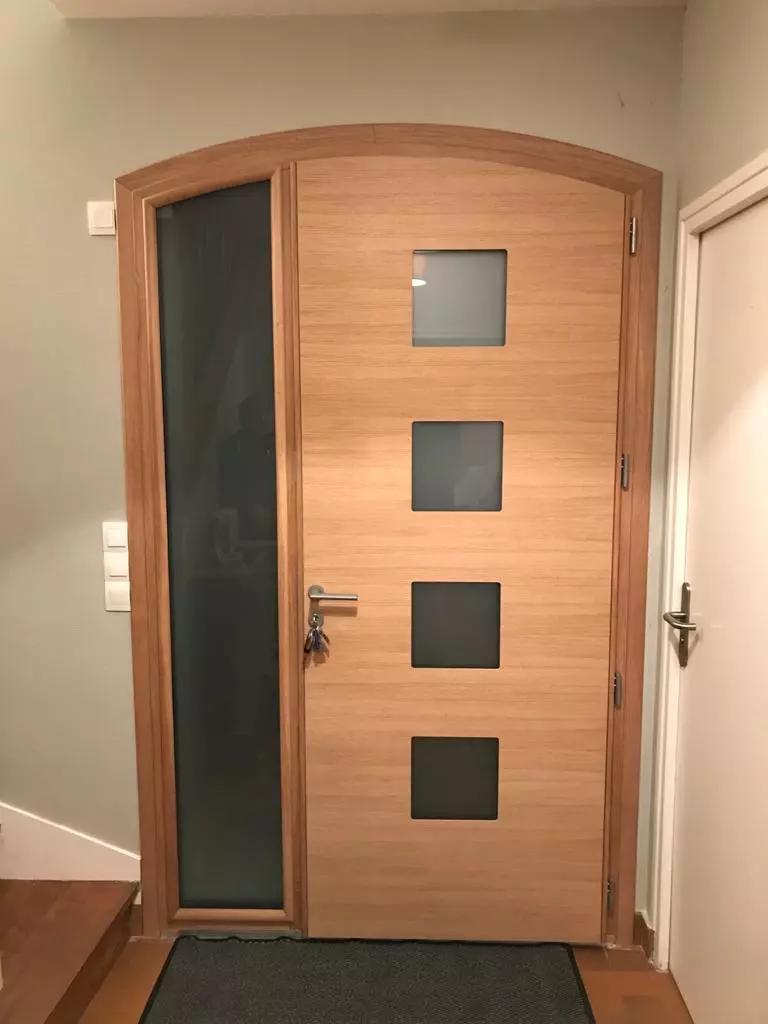 Porte d'entrée bois clair, imposte et quatre carreaux dépolis, poignée inox, vue intérieure