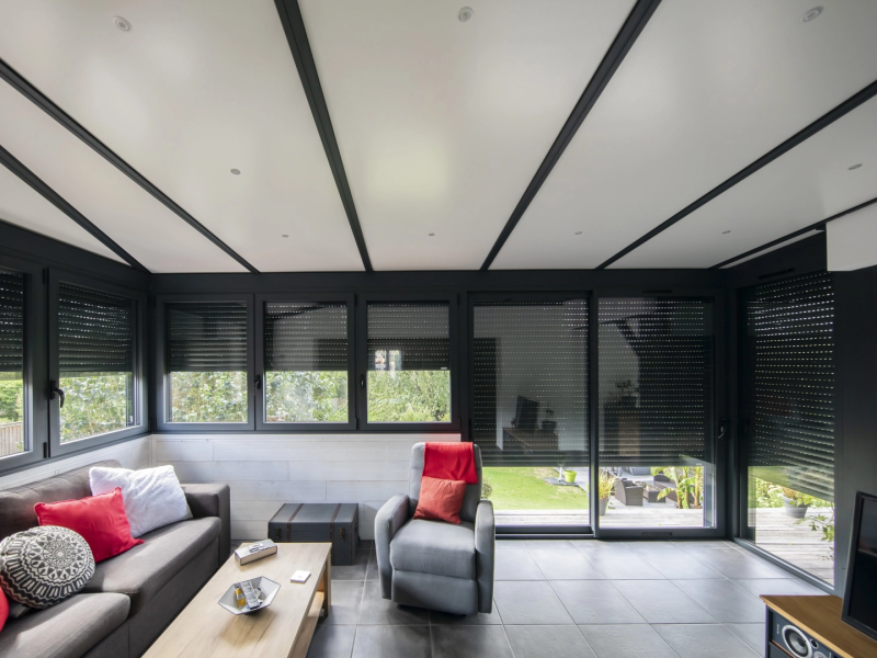 Intérieur véranda, menuiseries alu anthracite, volets roulants, plafond blanc spots
