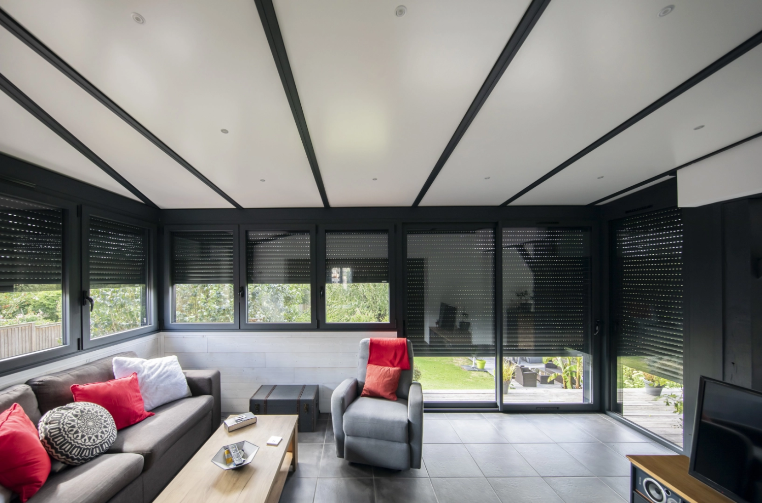 Intérieur véranda, menuiseries alu anthracite, volets roulants, plafond blanc spots