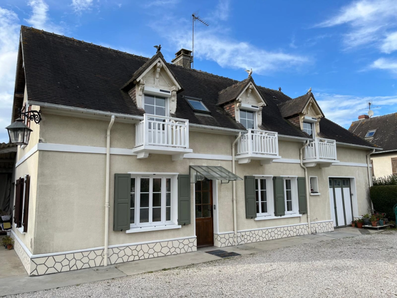 Maison crépi crème : fenêtres blanches, volets verts, garde-corps blancs aux lucarnes